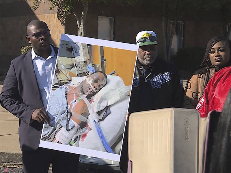 Tyre Nichols's stepfather Rodney Wells, centre, stands beside a photo of his son in hospital after his arrest. AP