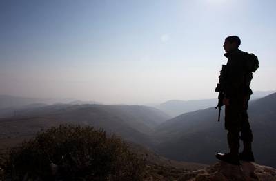 FILE PHOTO: File photo- An Israeli soldier stands guard during a tour made by Israeli parliament members in the Jordan Valley near the Jewish settlement of Maale Efrayim January 2, 2014.      REUTERS/Ronen Zvulun/File Photo
