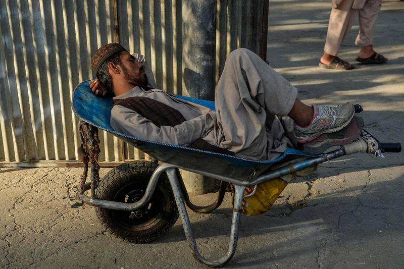 An Afghan man naps in a wheelbarrow. Photo: AFP