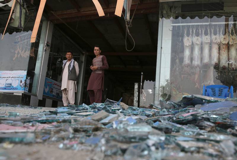 Afghans stand near a damaged shop after an explosion in Kabul, Afghanistan, Wednesday, Aug. 7, 2019. A suicide car bomber targeted the police headquarters in a minority Shiite neighborhood in western Kabul on Wednesday, setting off a huge explosion that wounded dozens of people, Afghan officials said. The Taliban claimed responsibility for the bombing. (AP Photo/Rafiq Maqbool)