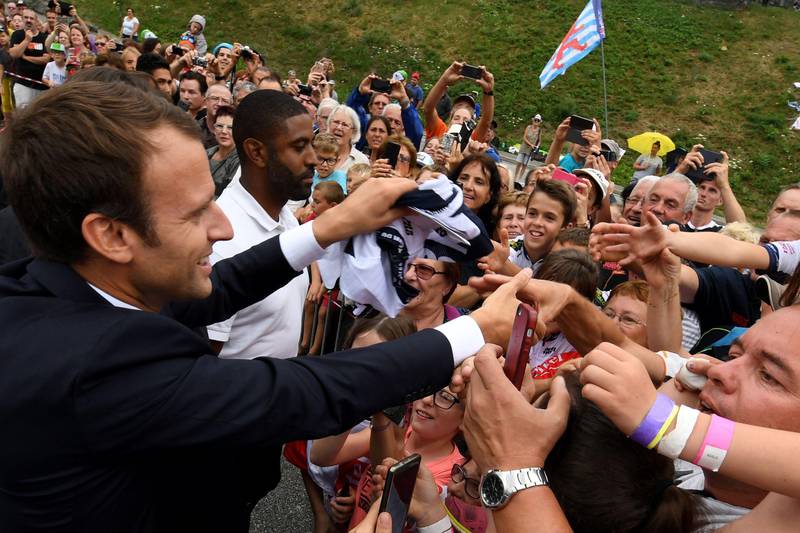 French President Emmanuel Macron (L) shakes hands with people as he arrives in Saint-Martin d'Arc, on July 19, 2017 to meet former cyclists and follow the 183 km seventeenth stage of the 104th edition of the Tour de France cycling race between Le La Mure and Serre-Chevalier, French Alps.  / AFP PHOTO / JEAN-PIERRE CLATOT