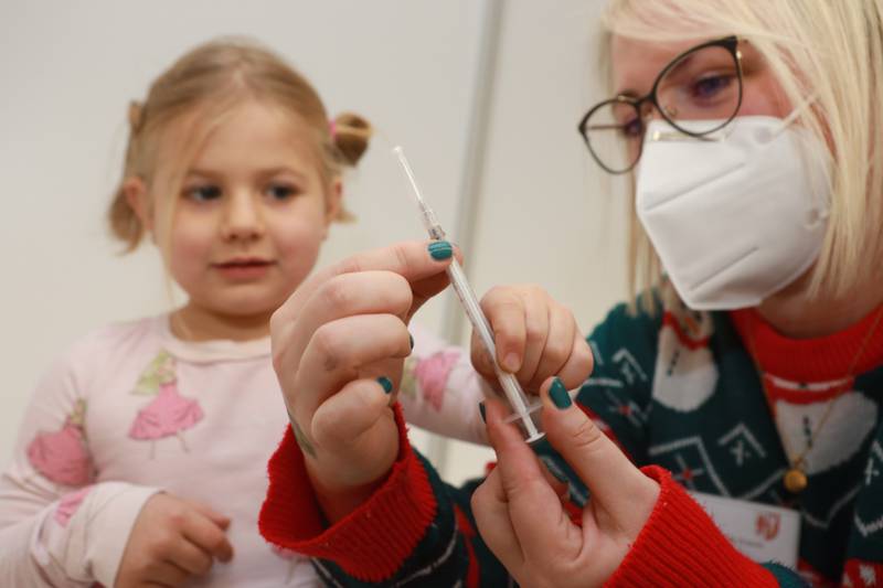 A girl of 5 is shown a syringe by a vaccination assistant before her first coronavirus vaccination in Germany. AP