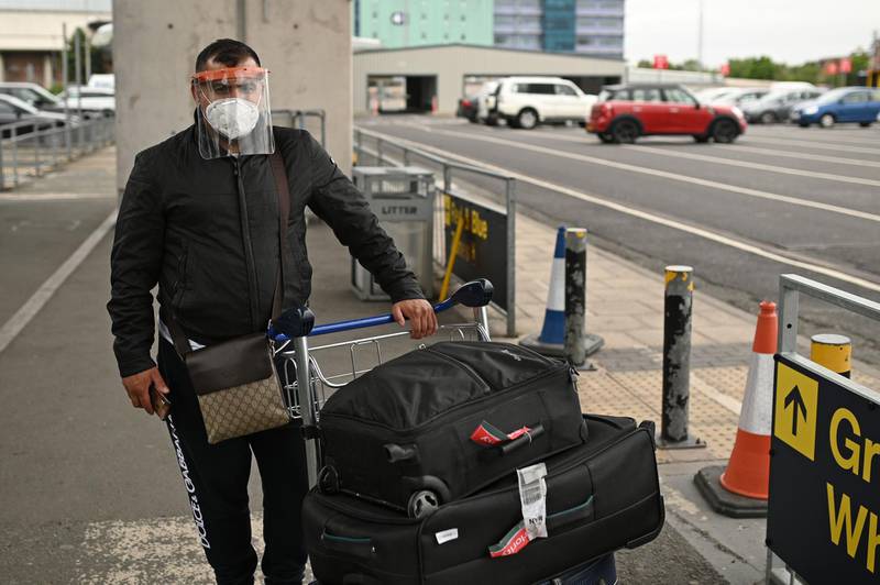 A passenger pushes his luggage after arriving at Manchester Airport. AFP
