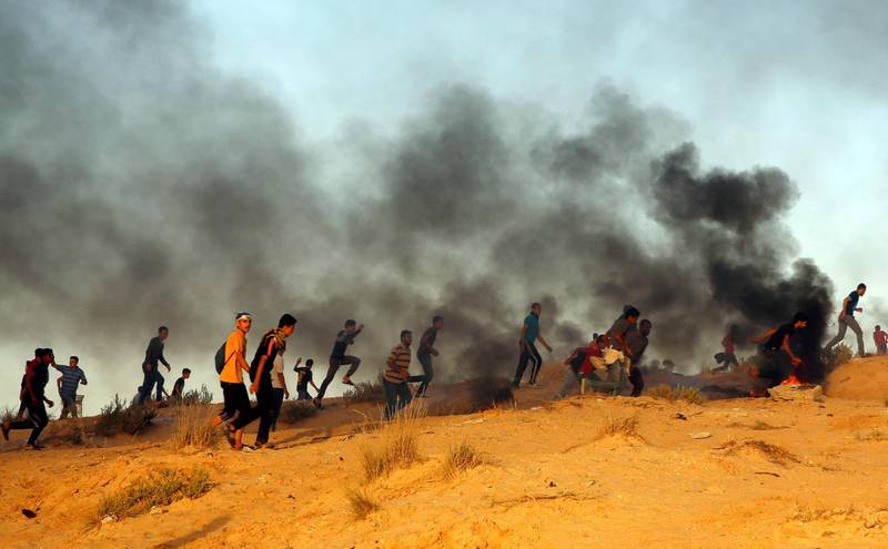 Protesters run to take cover from teargas fired by Israeli troops. AP Photo