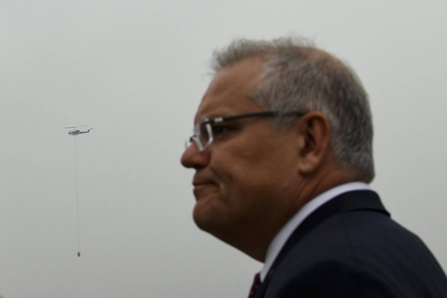 epa08103676 A fire fighting helicopter flies in the sky behind Australian Prime Minister Scott Morrison during a visit to HMAS Albatross in Nowra, New South Wales, Australia, 05 January 2020. According to media reports, at least 1,200 homes in Victoria and New South Wales have been destroyed by fires this season, at least 18 people have died, and more than 5.9 million hectares have been burnt.  EPA/LUKAS COCH / POOL AUSTRALIA AND NEW ZEALAND OUT