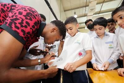 Shabab Al Ahli star Yahya Al Ghassani signs shirts of pupils at Dubai Carmel School.