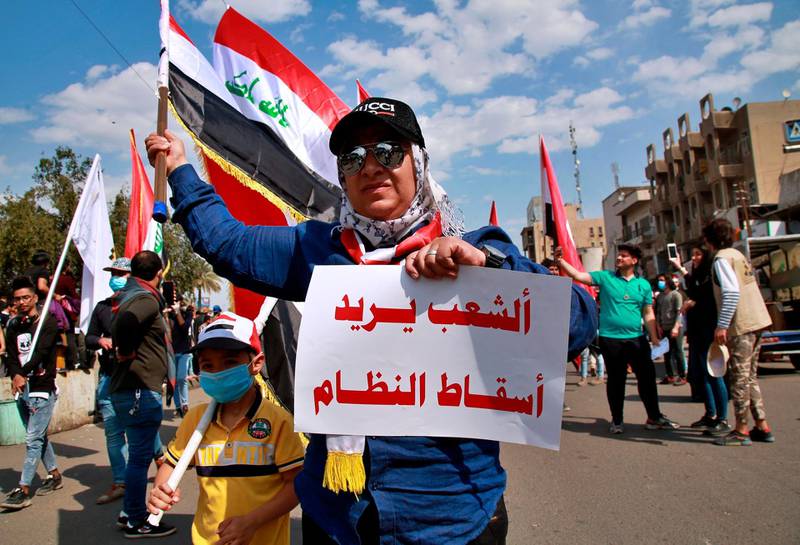 An anti-government protester holds a placard in Arabic that reads, "the people want to bring down the regime," during a rally in Baghdad, Iraq. AP Photo