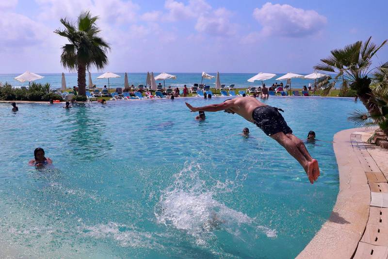 A man jumps into a swimming pool at Laguava Resort, in Rmaileh, south of Beirut as Lebanon has eased lockdown restrictions and reopened almost all businesses including beaches, pools, restaurants and cafes. AP Photo