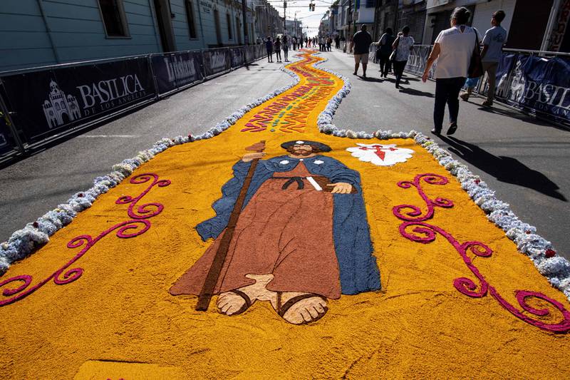 Parishioners walk in a street decorated with coloured carpets made of flowers, coloured sawdust and recycled plastic, for the procession of the Virgen de Los Angeles, in Cartago, Costa Rica. AFP