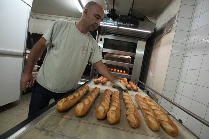 A baker takes baguettes out of an oven at a bakery in Versailles. The French baguette has been given Unesco World Heritage status. AP