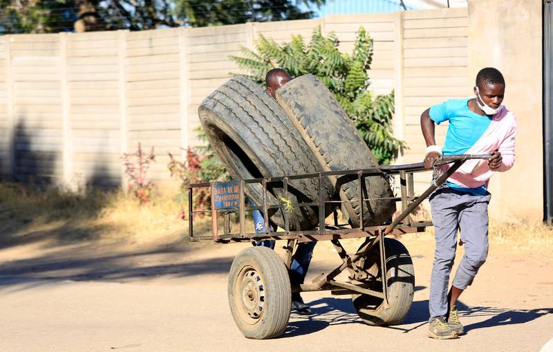 epa08465054 A man pulls a cart with used vehicle tyres for resale in an industrial area in Harare, Zimbabwe, 04 June 2020. The harsh economic situation in the country has forced many people to do anything in order to make a living. The Zimbabwe government has tightened screws on the lockdown soon after the number of those infected by the covid -19 pandemic  has risen.  EPA/AARON UFUMELI