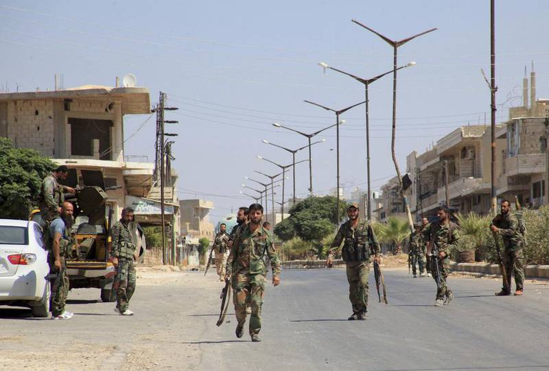 Forces loyal to Syrian president Bashar Al Assad walk through Halfaya in Hama province. George Ourfalian / Reuters