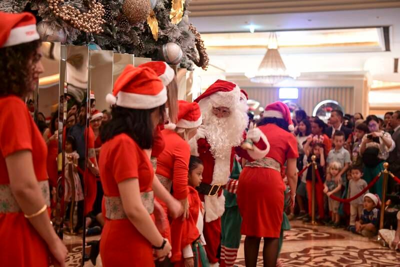 Santa Claus and his helpers by the Christmas tree at Emirates Palace. Khushnum Bhandari / The National

