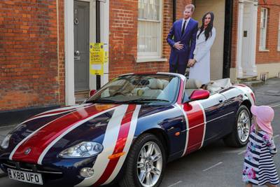 A girl looks at cardboard cut-out figures placed behind a Jaguar car in Union flag livery. Marko Djurica / Reuters