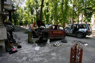 A man repairs a car in a residential area of Mariupol. AFP