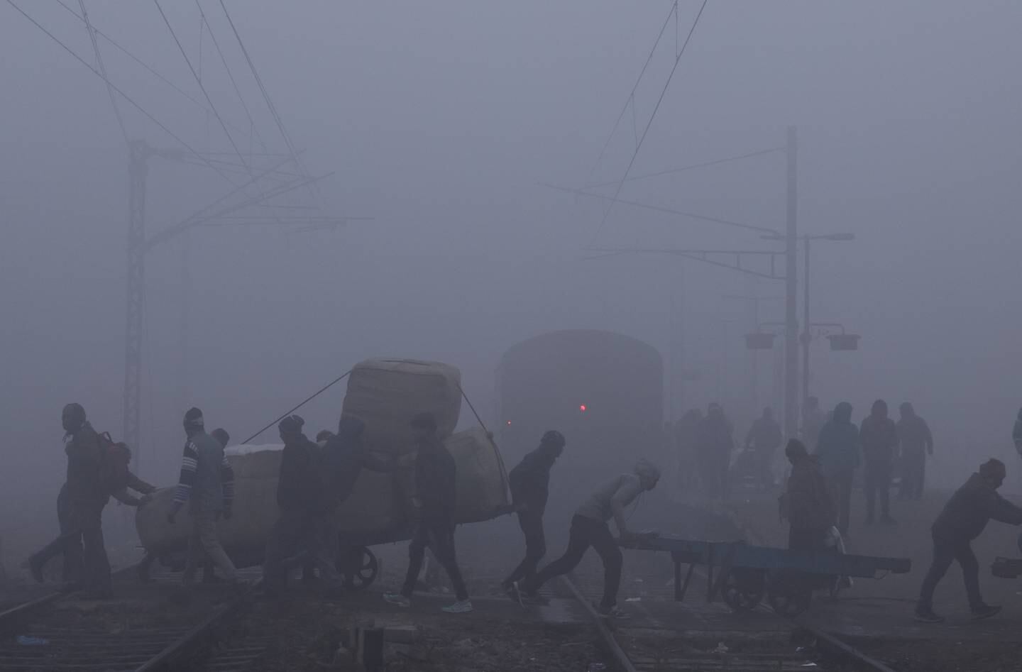 Labourers cross railway tracks amid heavy fog. Reuters