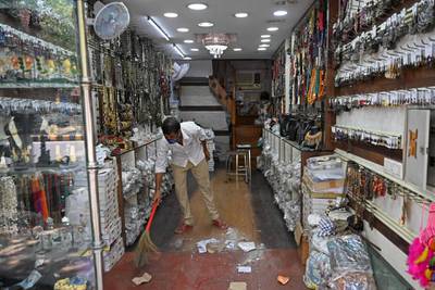 A shopkeeper cleans up after shops were allowed to reopen in New Delhi.