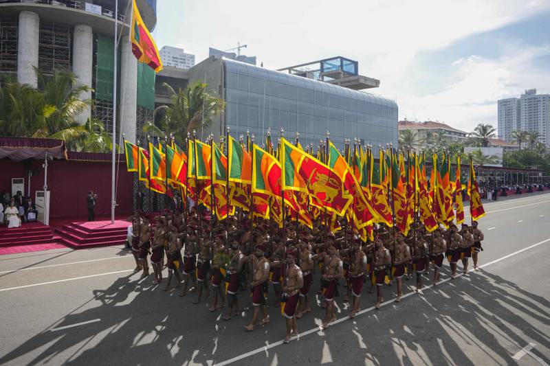 Sri Lankan government soldiers march carrying national flags. AP Photo 