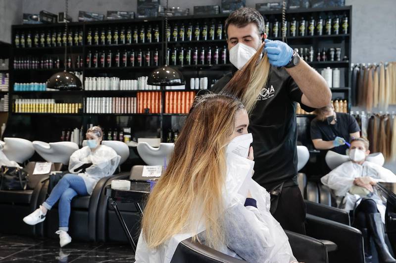 A hairdresser serves a customer in Naples, Italy, as the town is downgraded from a red to an orange zone, after weeks of tight restrictions to fight the coronavirus disease outbreak. Reuters
