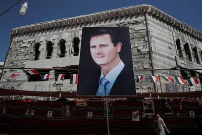 FILE PHOTO: A man walks past a banner depicting Syrian president Bashar al-Assad in Douma, outside Damascus, Syria, September 17, 2018. The town of Douma in eastern Ghouta was retaken by the government from rebels in April after heavy fighting and intense army bombardment and air strikes. REUTERS/Marko Djurica/File Photo