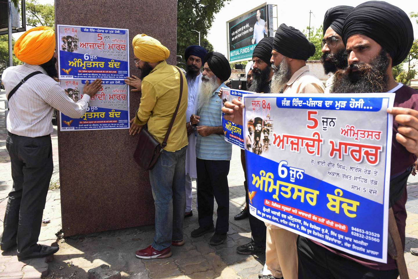 Activists of the Dal Khalsa Sikh organisation paste posters demanding a curfew from the authorities ahead of the 38th anniversary of the Operation Blue Star, in which Indian military on June 1984 assaulted the Golden Temple in Amritsar to flush out militants, in Amritsar on June 2, 2022.  (AFP)