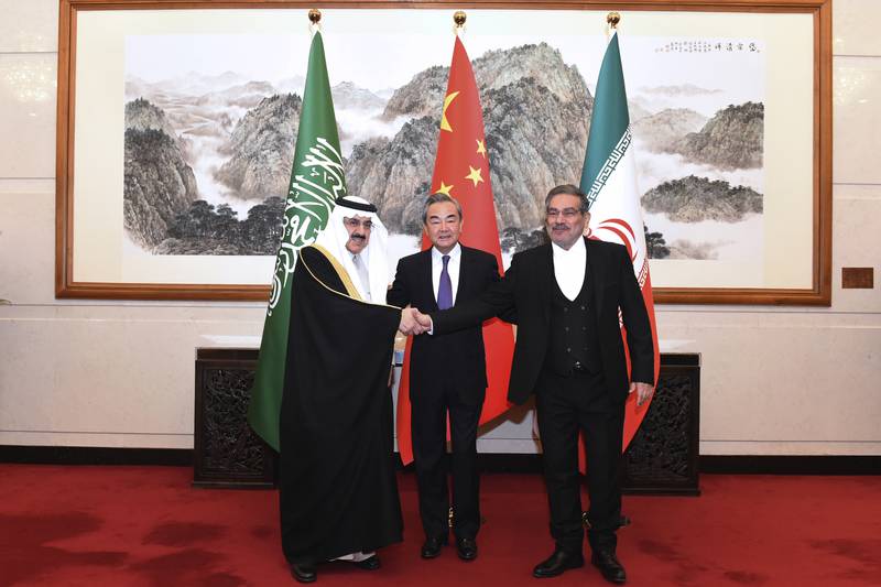 Ali Shamkhani, the secretary of Iran's Supreme National Security Council, right, shakes hands with Saudi national security adviser Musaad bin Mohammed Al Aiban, as Wang Yi, China's most senior diplomat, looks on, in Beijing, on March 11. AP