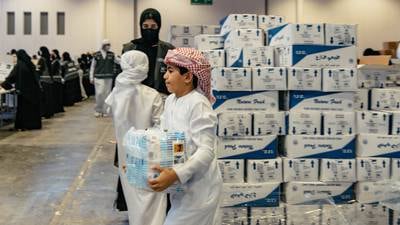 Boys carry the supplies for packing, at Sharjah Expo Centre. Photo: Issa Alkindy for The National