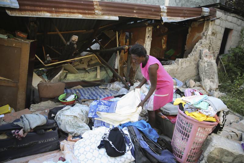 A woman recovers belongings after her home was destroyed by the earthquake. AP