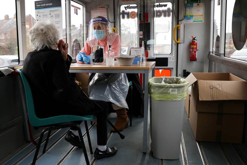 A healthcare worker shows an elderly woman how to take her swab sample, at a minibus that was converted into a mobile test centre in Walsall. Reuters
