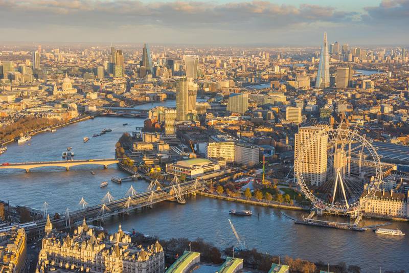 Aerial view across the River Thames and the Southbank, also showing the London Eye and surrounding Lambeth all bathed in warm sunlight.