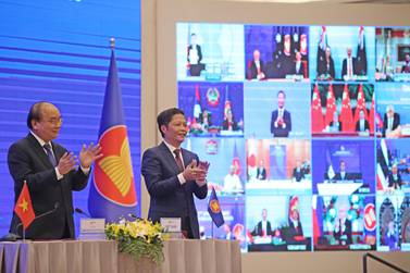Vietnam's Prime Minister Nguyen Xuan Phuc, left, and Minister of Industry and Trade Tran Tuan Anh applaud in Hanoi following the online signing of the Regional Comprehensive Economic Partnership. EPA