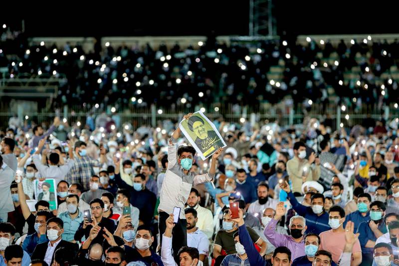 In this Wednesday, June 9, 2021 photo, a supporter of the presidential candidate Ebrahim Raisi, currently judiciary chief, hold his posters during a campaign rally at the Takhti Stadium in Ahvaz, Iran. Around 5,000 of people have gathered in a football stadium in southeastern city of Ahvaz to support the Iranian hard-line presidential candidate, Iranian media reported. (Alireza Mohammadi/ISNA via AP)