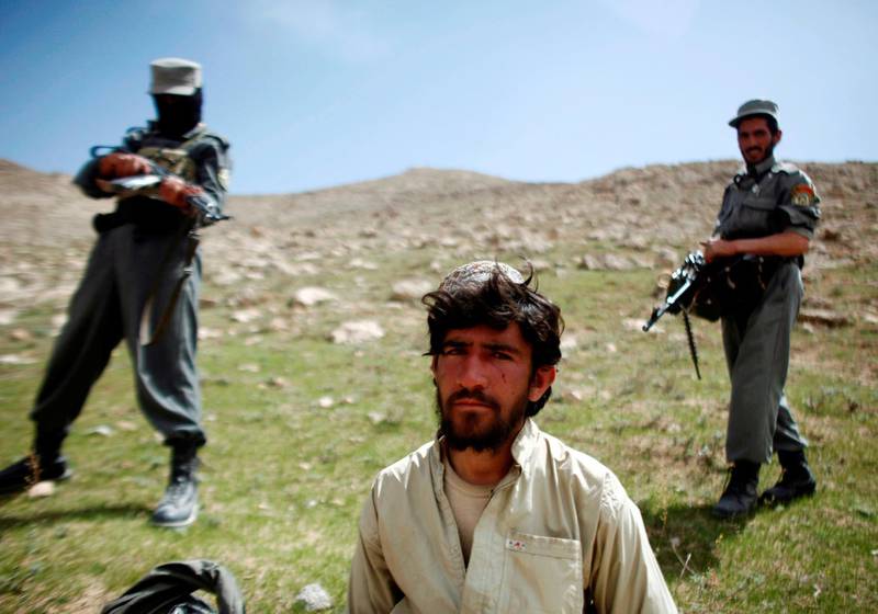 Afghan policemen stand next to a captured Taliban fighter after a gun battle near the village of Shajoy in Zabol province, Afghanistan March 22, 2008. Reuters