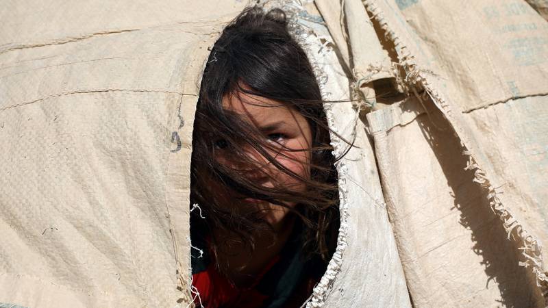 An internally displaced Afghan girl who fled her home due to fighting between the Taliban and Afghan security personnel, peers from her makeshift tent at a camp on the outskirts of Mazar-e-Sharif, northern Afghanistan. AP Photo