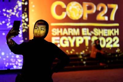 A Cop27 sign in Sharm El Sheikh, Egypt, provides the backdrop for this woman's selfie. Reuters
