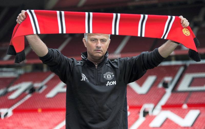 Manchester United's new Portuguese manager Jose Mourinho poses with a scarf on the pitch during a photocall at Old Trafford stadium in Manchester, northern England, on July 5, 2016. - Jose Mourinho officially started work as Manchester United manager at the club's Carrington training base yesterday. The 53-year-old was appointed as United boss in May after the sacking of Dutchman Louis van Gaal. (Photo by OLI SCARFF / AFP)