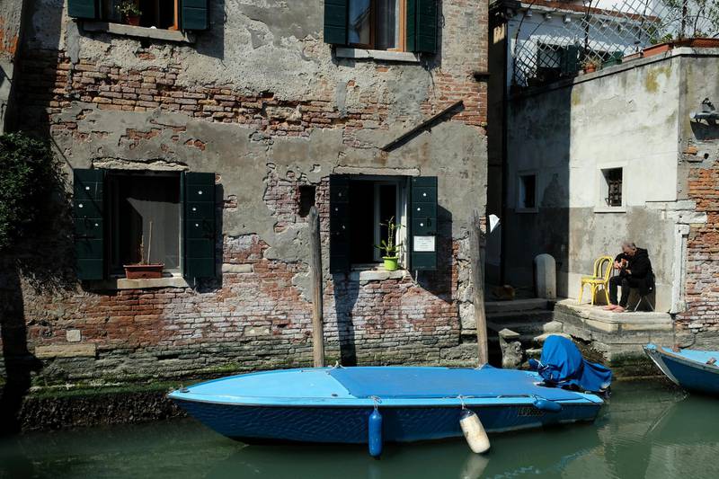 A man plays the guitar outside his apartment next to a deserted canal in Venice, Italy. Reuters