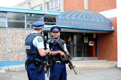 DUNEDIN, NEW ZEALAND - MARCH 16:  Police look on as locals lay flowers and condolences at the Huda Mosque in tribute to those killed and injured at the Al Huda Mosque  on March 16, 2019 in Dunedin. At least 49 people are confirmed dead, with more than 40 people injured following attacks on two mosques in Christchurch on Friday afternoon. 41 of the victims were killed at Al Noor mosque on Deans Avenue and seven died at Linwood mosque. Another victim died later in Christchurch hospital. Three people are in custody over the mass shootings. One man has been charged with murder.  (Photo by Dianne Manson/Getty Images)