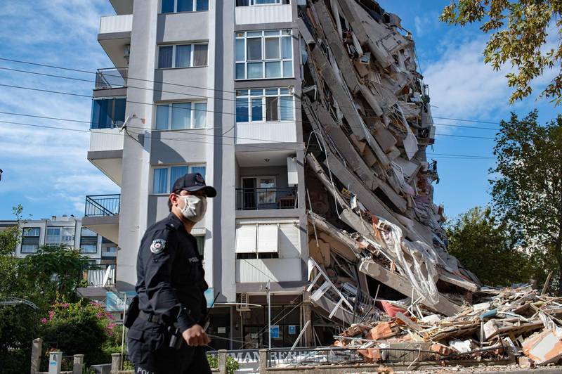 A police officer walks in front of a damaged building in Izmir, after a powerful earthquake struck Turkey's western coast and parts of Greece. AFP