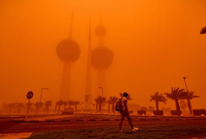 A man walks past the Kuwait Towers shrouded in heavy dust, in Kuwait City. EPA