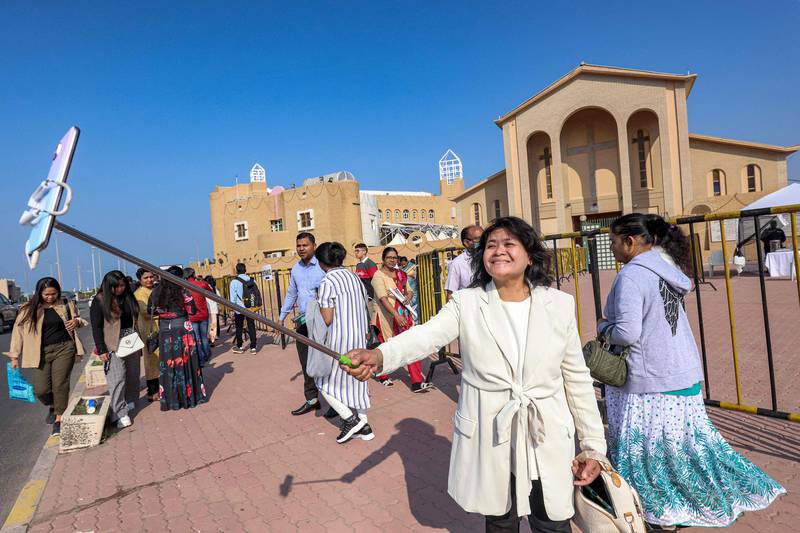 A woman uses a phone on a selfie stick to take a photo outside the Catholic Co-Cathedral of the Holy Family in Kuwait City on Christmas. AFP