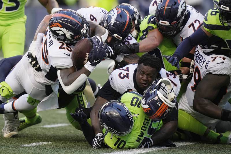 Denver Broncos' running back Melvin Gordon III, upper left, fumbles the ball as Broncos' offensive tackle Cameron Fleming (73) loses his helmet during an NFL football game against the Seattle Seahawks. AP