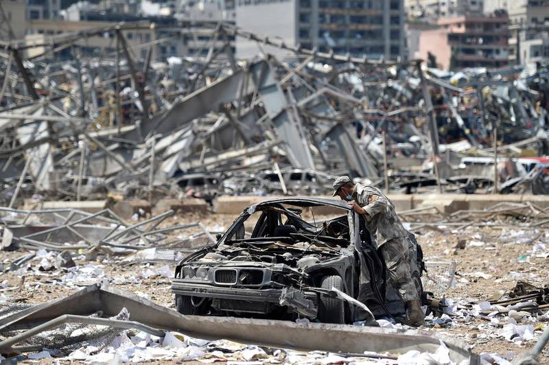 A Lebanese soldier looks at a damaged car.  EPA