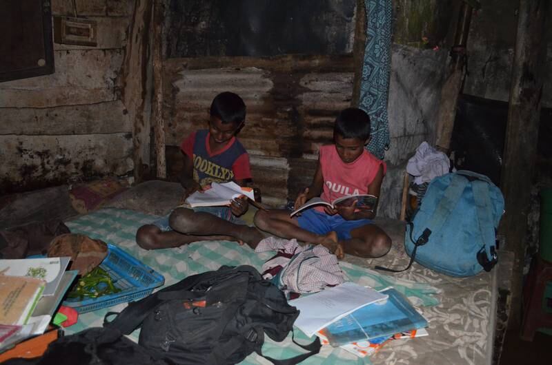 Children of the Thanaluxmy family study in the dark, at the tea plantation where they live. 