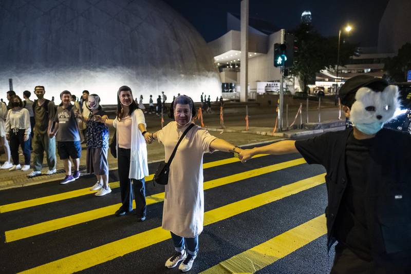 Demonstrators wearing face masks cross a road while forming a human chain during the Face Mask Way event in the Tsim Sha Tsui district of Hong Kong, China. Bloomberg