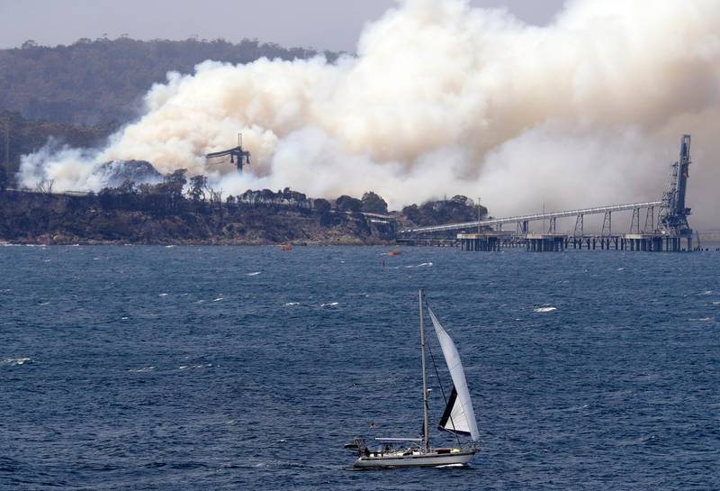 A yacht sails past a burning woodchip mill as the wildfires hits the town of Eden, New South Wales, Australia. The wildfires have destroyed more than 2,000 homes and continue to burn, threatening to flare up again as temperatures rise. AP Photo