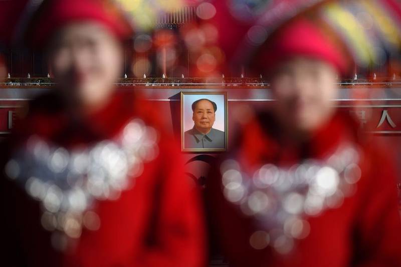A portrait of late communist leader Mao Zedong is seen behind two hostesses as they pose for a picture at the Tiananmen Square during the 3rd plenary session of the National People’s Congress in Beijing.   China’s Communist-controlled parliament opened its annual session on March 5 and is expected to approve a new five-year plan to tackle slowing growth in the world’s second-largest economy. Wang Zhao / AFP