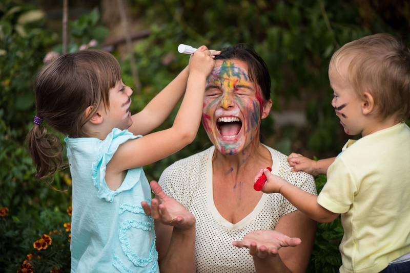 Children are painting mother's face with body colours outside - mother got beyond happiness level from playing with kids