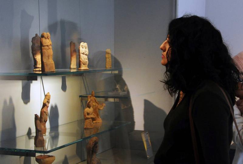 In this photo released by the Syrian official news agency SANA, a visitor looks at ancient artifacts during the reopening ceremony for  Syria's National Museum, in Damascus, Syria, Sunday, Oct. 28, 2018. Syrian officials, foreign archeologists and restoration specialists attended the Sunday reopening ceremony in the heart of Damascus more than six years after the prominent institution was shut down and emptied as the country's civil war encroached on the capital. (SANA via AP)