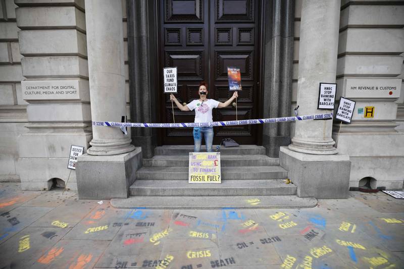 A climate activist demonstrates on the steps of the HM Revenue & Customs office. AFP